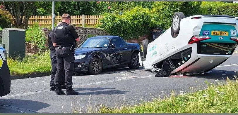 Taxi Overturns on Manor Road: Driver Hurt as Cab Crashes into Parked Car